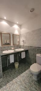 ein Badezimmer mit zwei Waschbecken und einem WC in der Unterkunft Hôtel Côté Jardin in Commercy
