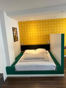 ein Schlafzimmer mit einem Bett mit gelber Wand in der Unterkunft Tondose Apartment in Dortmund