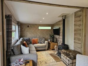a living room with a couch and a stove at Rowan Tree Lodge with hot tub in Hope Bagot