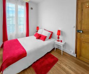 um quarto com uma grande cama branca com almofadas vermelhas em Porte de Paris Élégance à Vitry-sur-Seine em Vitry-sur-Seine