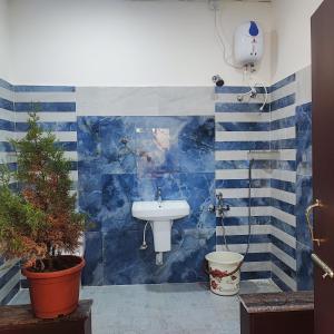 baño con lavabo y pared de azulejos azules en Maha Periyava Kuteeram en Kumbakonam