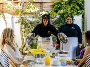 a group of people standing around a table with food at Fleur du Soleil Luxury Guesthouse in Franschhoek