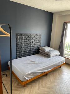 1 cama en un dormitorio con una pared azul en Hostel UND BASE en Saiki