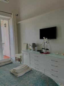 Capri Suite Dreams في كابري: غرفة نوم مع خزانة مع تلفزيون على الحائط