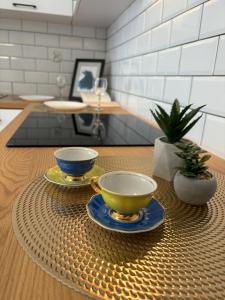 two cups and saucers sitting on a table at Apartament White glove Nowe Zatorze in Olsztyn