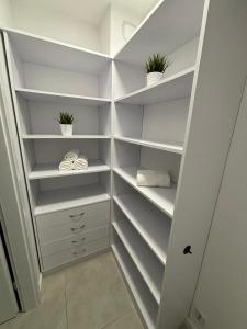 a walk in closet with white shelves and potted plants at Apartament White glove Nowe Zatorze in Olsztyn