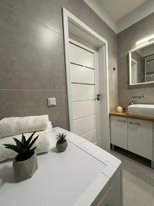a bathroom with a white table and a sink at Apartament White glove Nowe Zatorze in Olsztyn