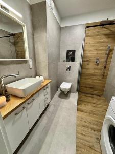 a bathroom with a sink and a toilet and a shower at Apartament White glove Nowe Zatorze in Olsztyn