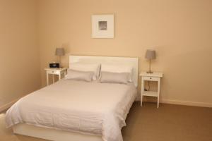 a bedroom with a white bed with two night stands at The Lighthouse - Beachfront Accommodation in Port Hughes