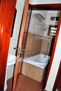 a bathroom with a toilet and a tub and a sink at Kisoro Homely Suites in Kisoro