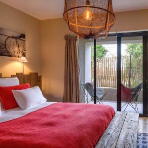 a bedroom with a large bed with a red blanket at Domaine Tarbouriech, Hôtel & Spa in Marseillan