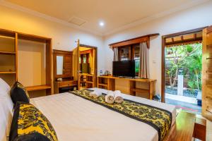 a bedroom with a bed with two towels and a television at Paradise Luxury Villa in Gili Air