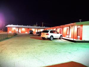 un coche blanco estacionado frente a un edificio por la noche en Holiday Host Motel & RV Park, en Sonora