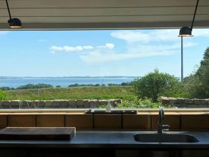 una cucina con una grande finestra sopra un lavandino di Luxury house with breathtaking sea view of Mols a Rønde