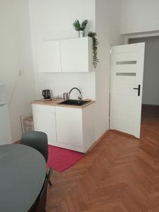 uma cozinha com um lavatório, uma mesa e uma porta em Apartament Batorego em Cracóvia