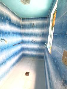 a blue tiled bathroom with a tub with a window at JocoHideaway in Jocotitlán