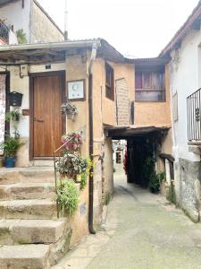 un callejón con un edificio con una puerta de madera en El Balcon de Justina - Sierra de Gata, en Torre de Don Miguel