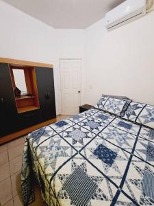 a bedroom with a bed with a blue and white quilt at casa familiar san miguel in San Miguel