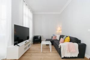 ein Wohnzimmer mit einem schwarzen Sofa und einem TV in der Unterkunft Estilo, luz y elegancia en Vigo by CABANA Rentals in Vigo