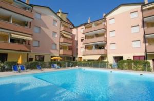 a swimming pool in front of some apartment buildings at Seaside serenity flat with outdoor pool in Rosolina Mare