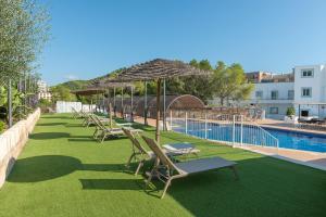 eine Reihe von Stühlen und Sonnenschirmen neben einem Pool in der Unterkunft Villa Real Club Apartments in Camp de Mar