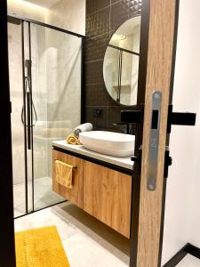 a bathroom with a sink and a shower and a mirror at Apartament Niebo przy plaży in Ostróda