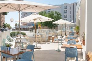 a patio with tables and chairs and umbrellas at Villa Real Club Apartments in Camp de Mar