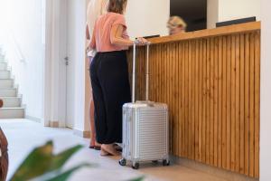 a woman standing next to a fence with a suitcase at Villa Real Club Apartments in Camp de Mar