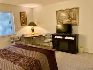 a bedroom with a bed and a tv and a table at Red Robe Chamber in Nanaimo