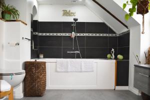 a bathroom with a white tub and a black tile wall at Manoir Drissia - Tours Centre, France in Saint-Avertin