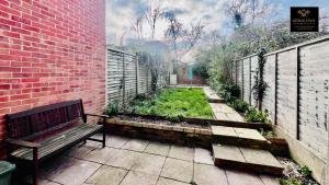 a bench sitting in a garden next to a brick wall at Brand New! The Cosy Cove by Artisan Stays I Free Parking I Sleeps 5 I Families or Contractors in Chelmsford