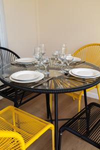 een zwarte tafel met glazen, borden en stoelen bij Cosy Studio Coeur de l'Océan vue mer et aéroport in Saint-Denis