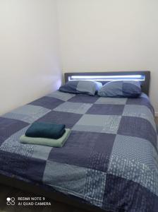 a bed with a blue and gray blanket and pillows at Blessing in Rosny-sous-Bois