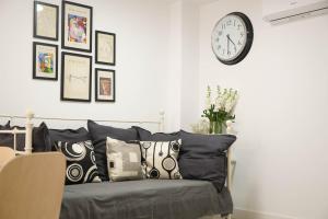 Habitación con sofá con almohadas y reloj en la pared. en Apartamento Ágüelos, en Madrid