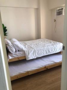 1 dormitorio con 2 literas con sábanas blancas en Fia Horizons @ Infina South Tower en Manila