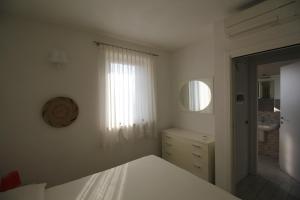 Habitación blanca con cama y espejo en Da Manu, en Negrar