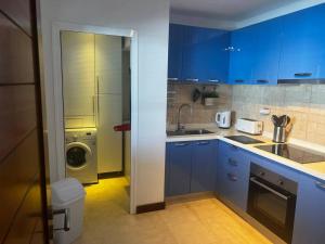 a kitchen with blue cabinets and a washing machine at Apartamento San Eloy con plaza de garaje in Playa Honda