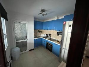 una pequeña cocina con armarios azules y nevera. en Apartamento San Eloy con plaza de garaje en Playa Honda