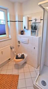 a white bathroom with a toilet and a window at Fewo Strandläufer Usedom im Grünen ruhig Terrasse Parkplatz in Ostseebad Karlshagen
