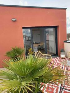 een huis met een patio met 2 stoelen en planten bij Le Rooftop d’Isa in Colombelles
