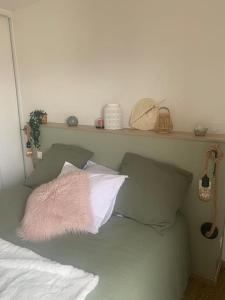 een slaapkamer met een bed met kussens en een plank bij Le Rooftop d’Isa in Colombelles
