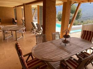 una mesa de madera y sillas en una habitación con piscina en La Bernardière du Ventoux 1, en Mollans-sur-Ouvèze