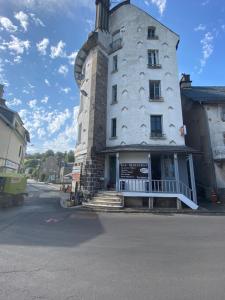 a tall white building with stairs in front of a street at Auberge la grange in Égliseneuve-dʼEntraigues