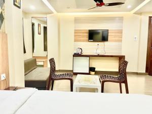um quarto com uma cama e duas cadeiras e uma televisão em Hotel Yashasvi ! Puri fully-air-conditioned-hotel near-sea-beach-&-temple with-lift-and-parking-facility breakfast-included em Puri