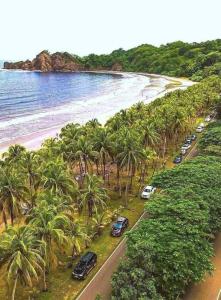 a bunch of cars parked on a beach with palm trees at Tabaco Lodge #2 a solo 5 minutos de Playa Carrillo in Carrillo