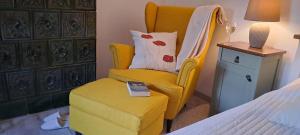 Un dormitorio con una silla amarilla y una cama en Lassu Tanya Vendégház, en Nagykőrös