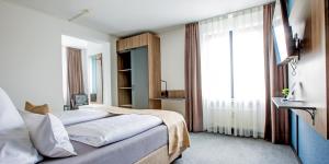 a bedroom with a bed and a large window at Hotel Das Augustin in Sankt Augustin