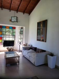 una sala de estar con sofá y vidrieras. en Quinta Oasis de Paz en Los Cardales en Campana