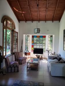 una sala de estar con sofás, TV y vidrieras. en Quinta Oasis de Paz en Los Cardales en Campana