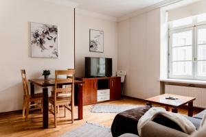 a living room with a table and a tv and a dining room at Town Hall Square Apartment with Sauna in Tallinn